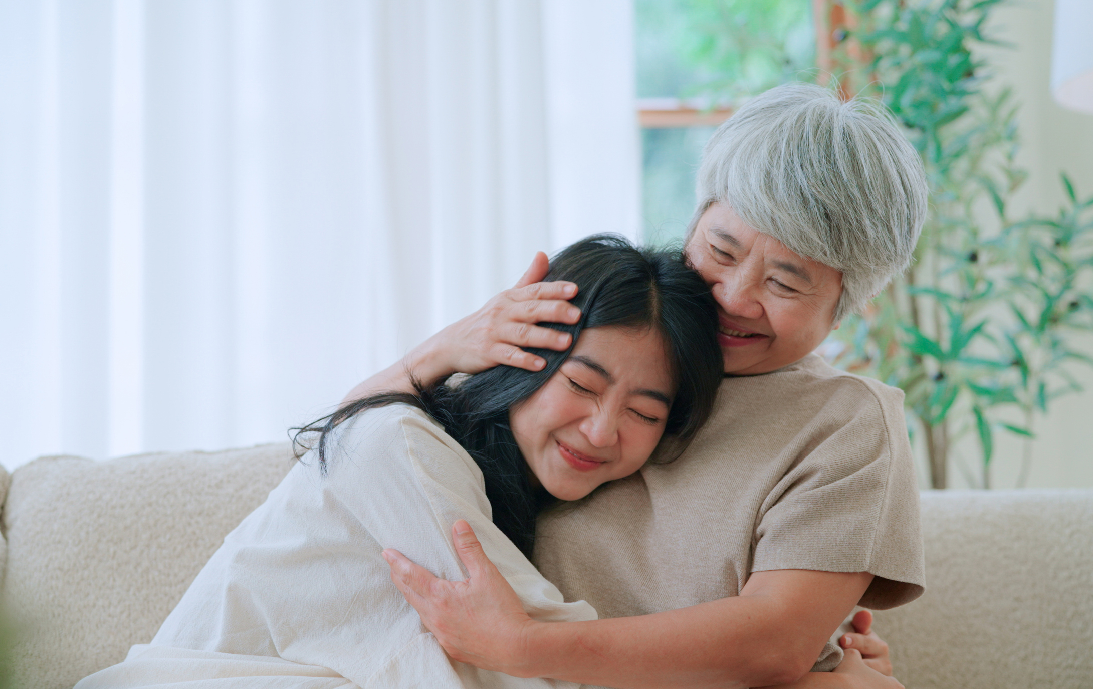 Younger woman hugging and being embraced by an older senior woman 