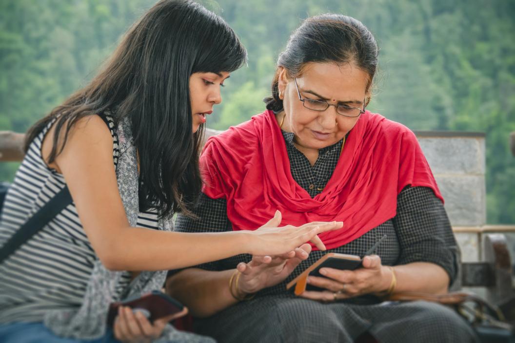 Young caregiver teaching senior elderly woman to use a phone app