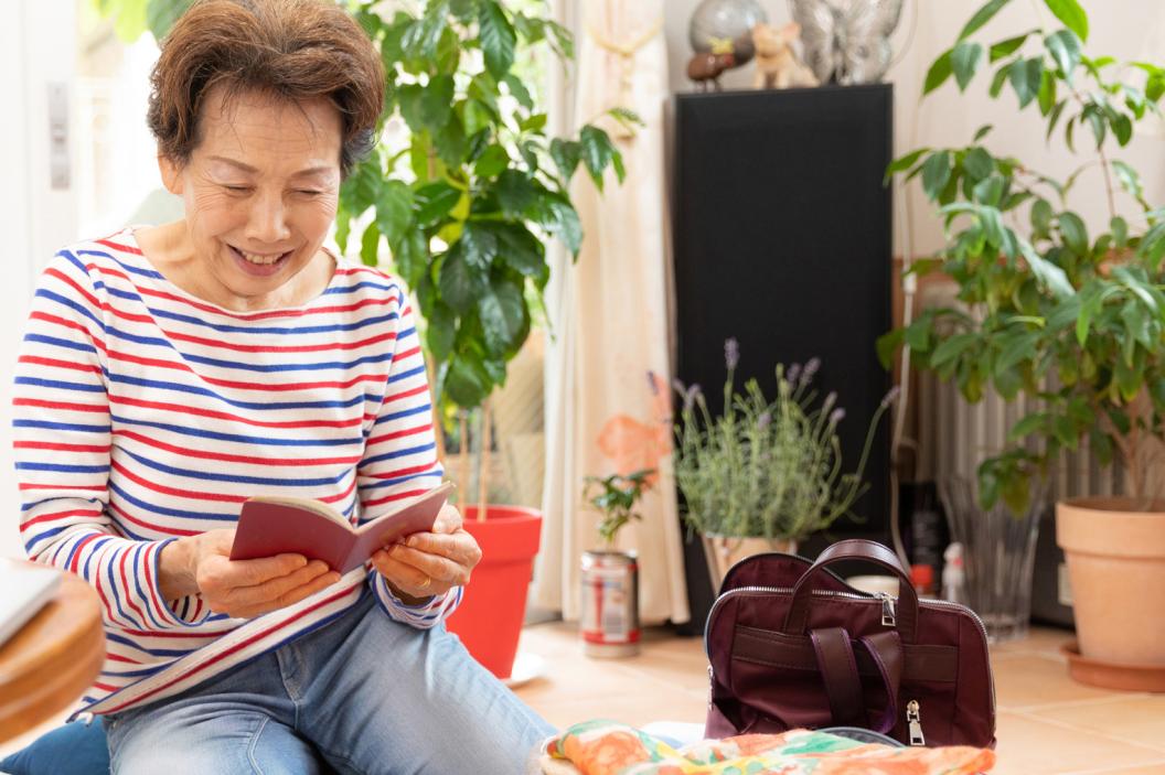 Senior elderly woman looking at passport while packing luggage